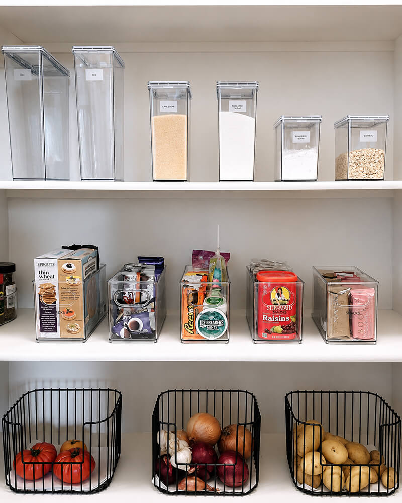 Perfectly labeled kitchen pantry shelves organized by Lifelystyle in Las Vegas — tall acrylic containers for dry goods, clear snack organizers, and wire produce baskets for an effortless daily routine