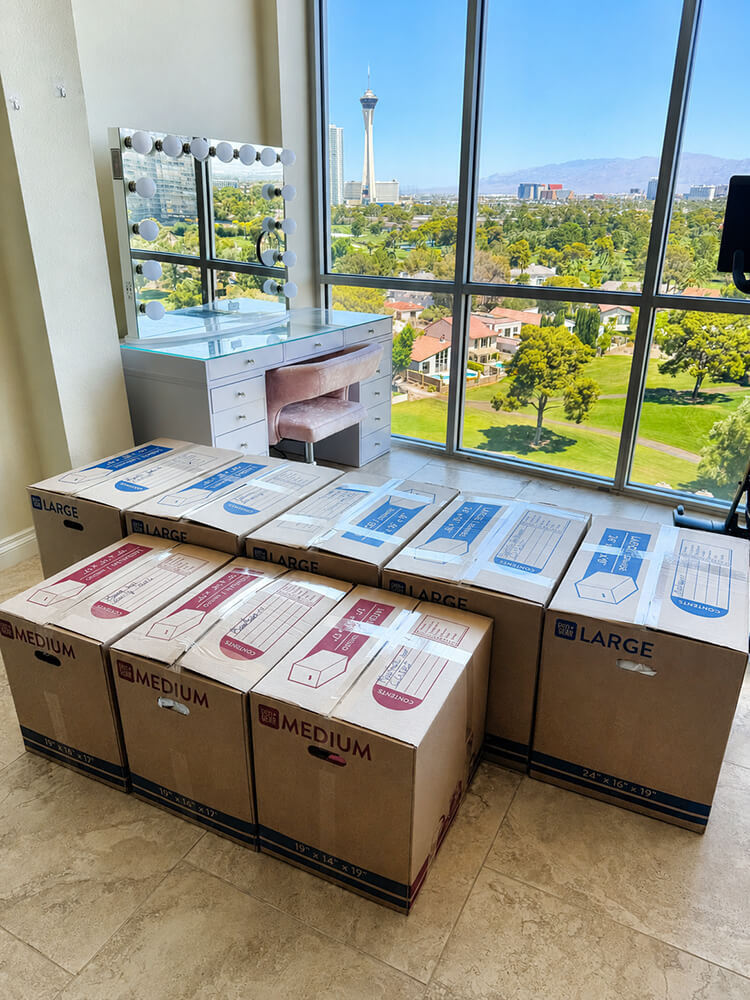 Moving boxes stacked in a high-rise Las Vegas residence with the Strip skyline visible through floor-to-ceiling windows — Lifelystyle move-in concierge transforms this into a fully organized home by end of Day One