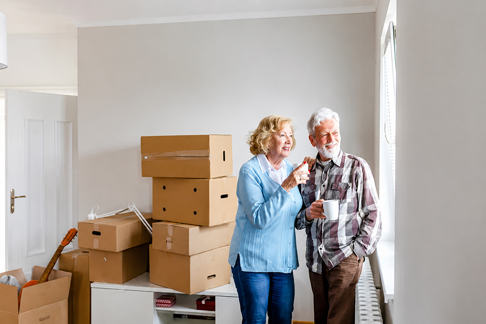 Smiling senior couple sharing a moment amid moving boxes during their downsizing transition in Las Vegas — Lifelystyle provides patient, compassionate support every step of the way
