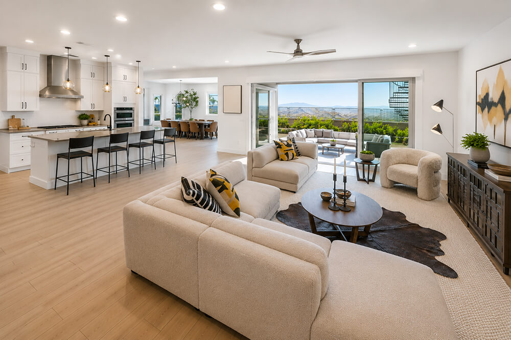 Professionally staged open-plan great room by Lifelystyle in Las Vegas — boucle sectional, cowhide rug, curated kitchen island styling and outdoor living continuity that sells the Las Vegas luxury lifestyle to high-end buyers