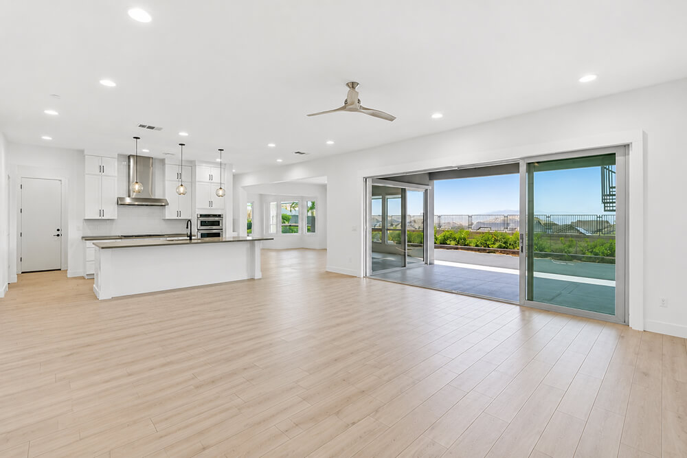 Vacant open-plan great room with kitchen island and terrace access before professional home staging by Lifelystyle in Las Vegas — empty space that fails to communicate scale or lifestyle to luxury buyers